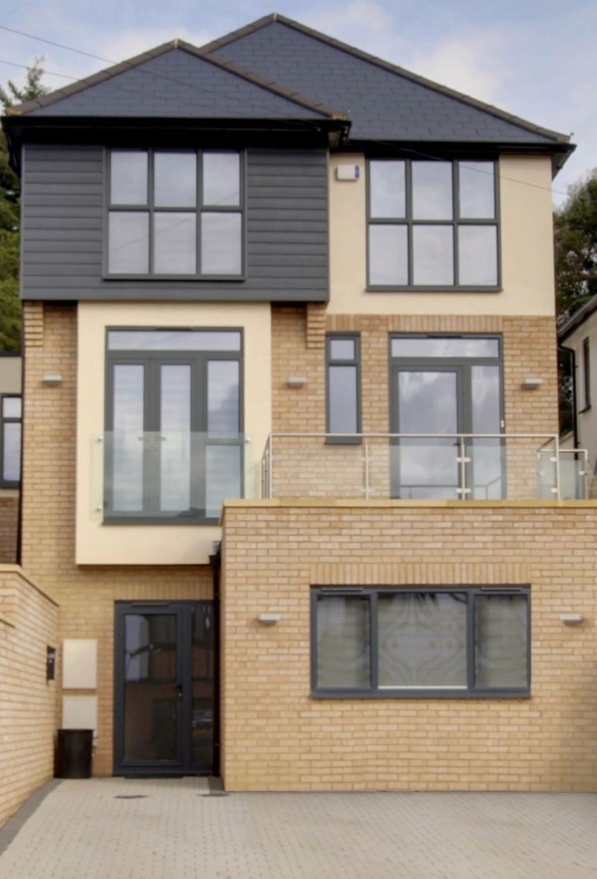 Modern two-story brick house with large windows and glass balcony.