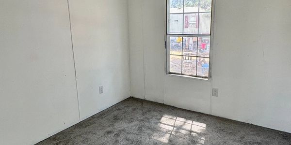 Empty room with carpet and a window letting in sunlight.