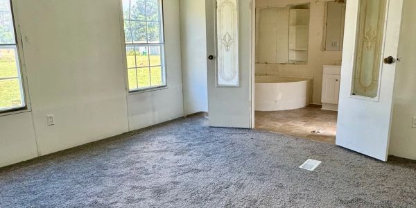 Empty room with gray carpet and open doors leading to a bathroom.