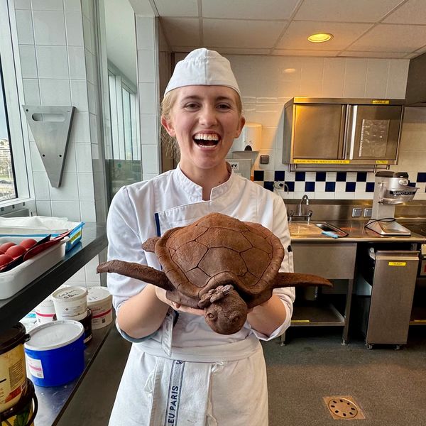 Chef holding a turtle-shaped bread in a kitchen.