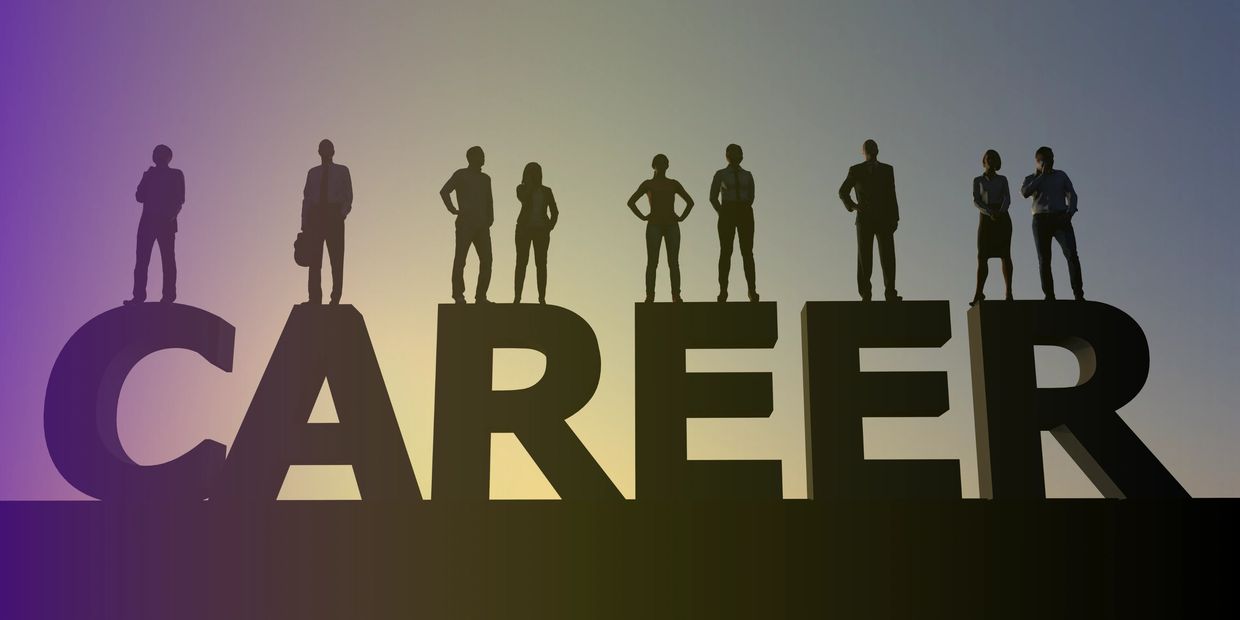Silhouetted professionals standing on large letters spelling CAREER at sunset.