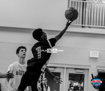 Black-and-white action shot of a basketball player attempting a layup during a game.