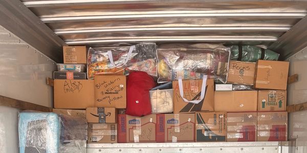 Packed moving truck with labeled boxes and bags.