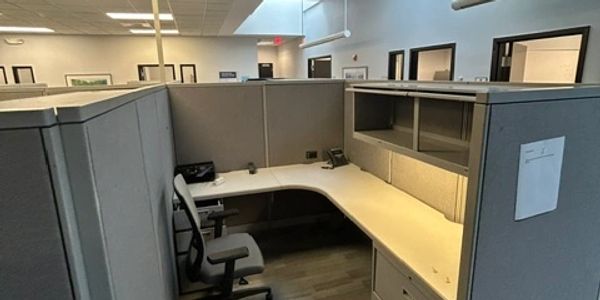 Empty office cubicle with chair and phone.