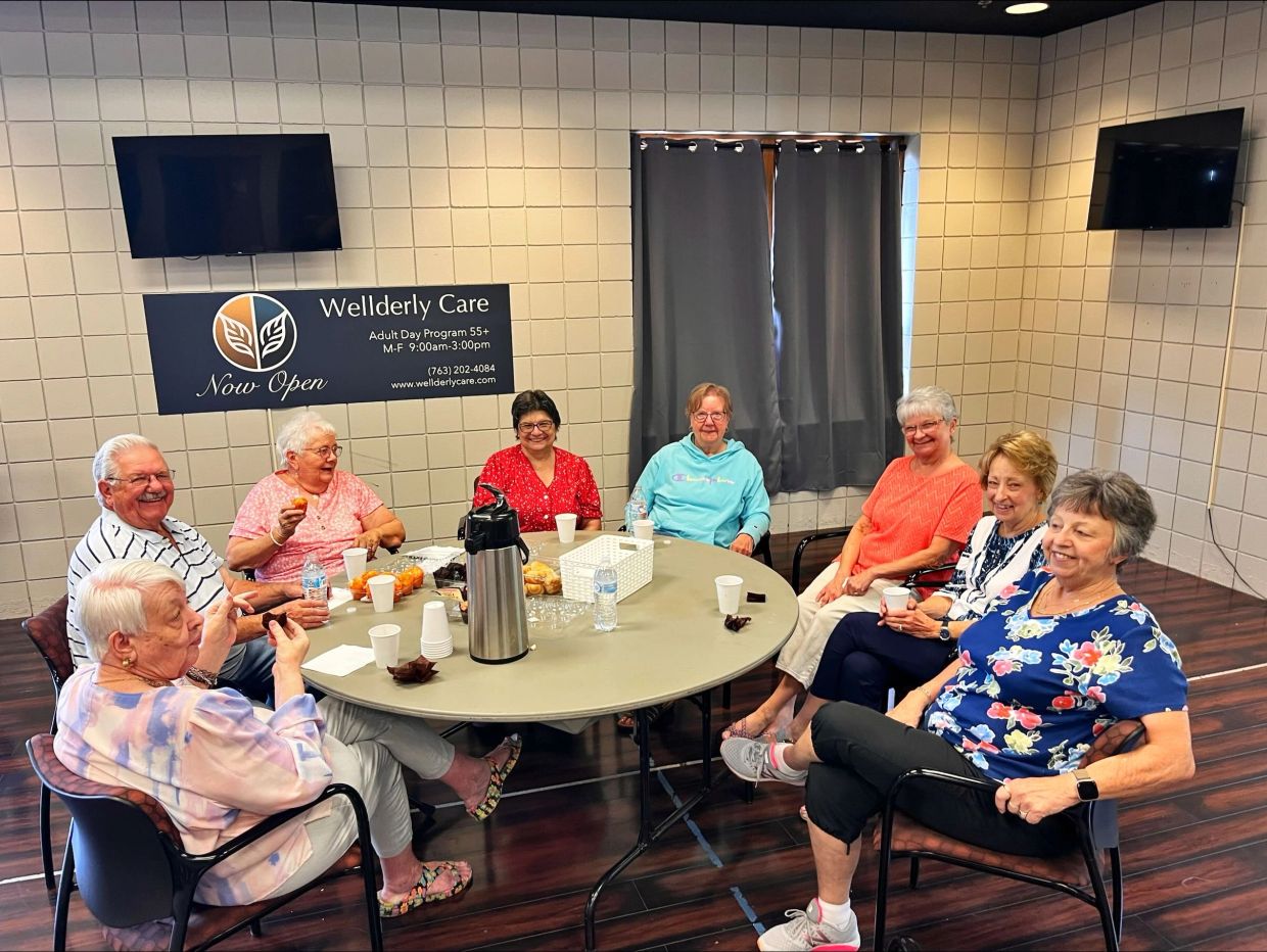 Group of 8 seniors enjoying coffee and snacks. some looking, some talking and some eating 