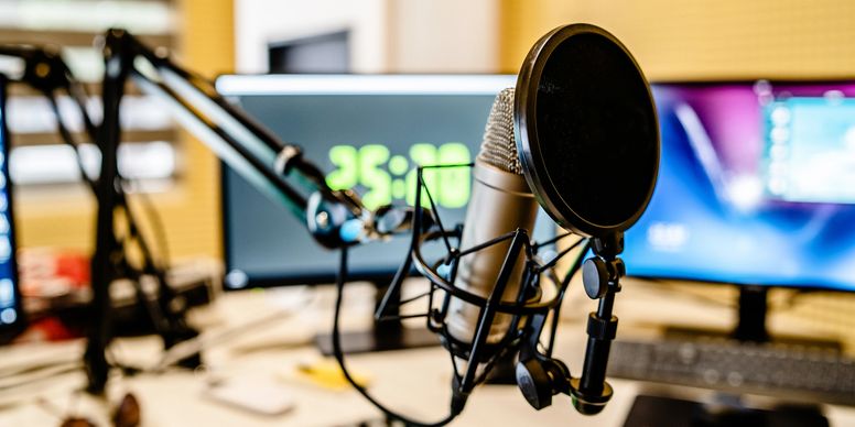 A professional podcasting microphone and headphones in a studio setting.