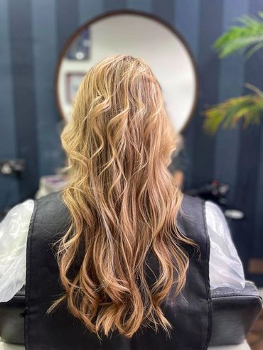 Soft golden blonde balayage on long wavy hair, freshly styled at Santoro Hair Salon in Brighton. 