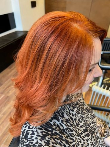 Vibrant copper-red hair colour with soft layered waves created at Santoro Hair Salon in Brighton. Th