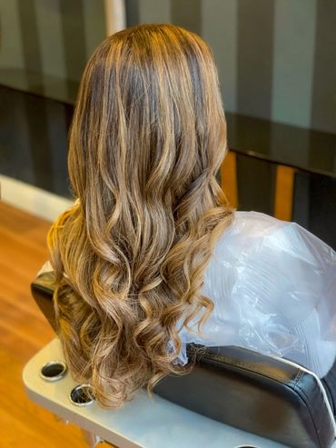 Warm caramel balayage with soft curls created at Santoro Hair Salon in Brighton. The blended highlig