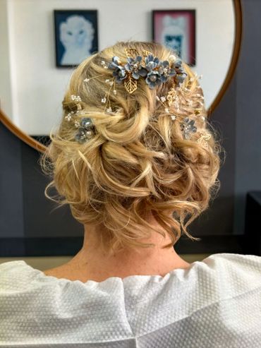 Elegant bridal updo with soft curls and delicate floral hair accessories, styled at Santoro Hair Sal