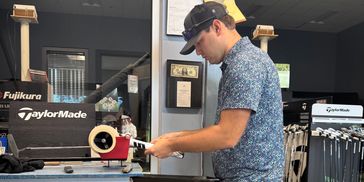 A young man inspecting a golf club in a golf store.