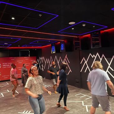 People dancing in a modern, neon-lit room with geometric wall designs.