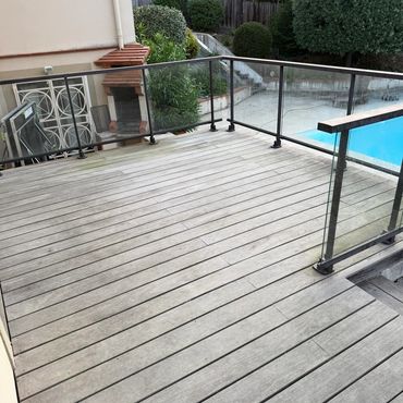 Terrasse en bois avec une piscine à côté.