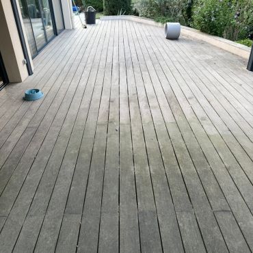 Terrasse en bois avec quelques objets et peu de végétation.