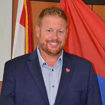Young man with red hair and red beard smiling, wearing a blue suit