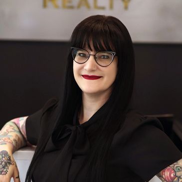 Young woman with black hair and black glasses smiling