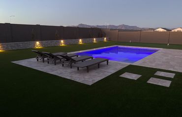 backyard landscape with travertine, retaining wall, pool, mini golf and turf in Arizona 