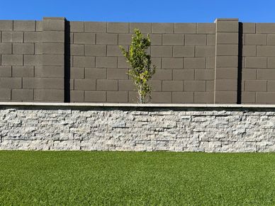 beautifully built retaining wall with turf and fica trees