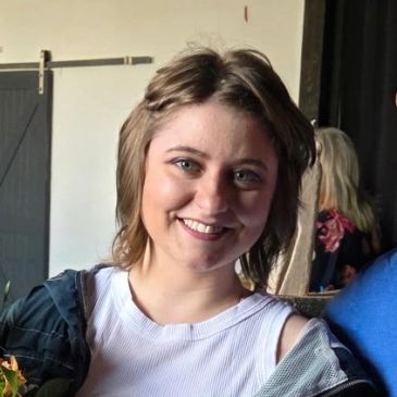 Smiling young woman with short hair in casual attire.