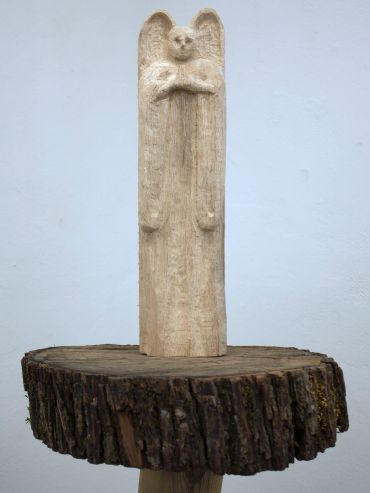Wooden angel sculpture on a tree stump.