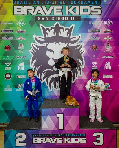 Young competitors on podium at Brave Kids Brazilian Jiu-Jitsu Tournament in San Diego.