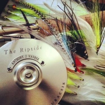 Close-up of a fishing reel and colorful fishing flies.