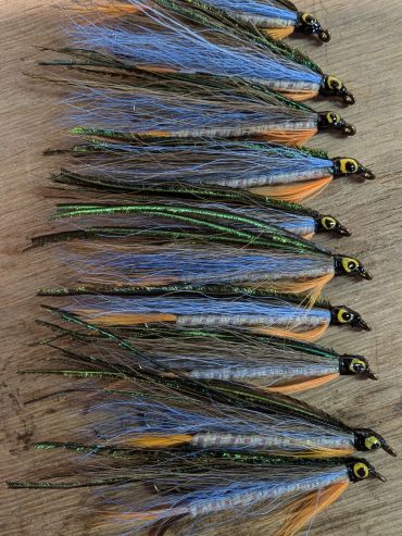 Row of detailed fishing flies with blue and green feathers.