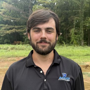 Smiling man outdoors in a black polo shirt.