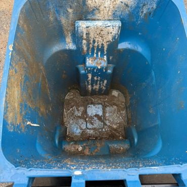 Dirty blue plastic container with mud inside.