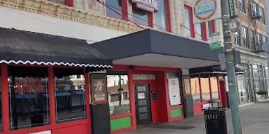 A vintage red and black theater entrance on a city street.