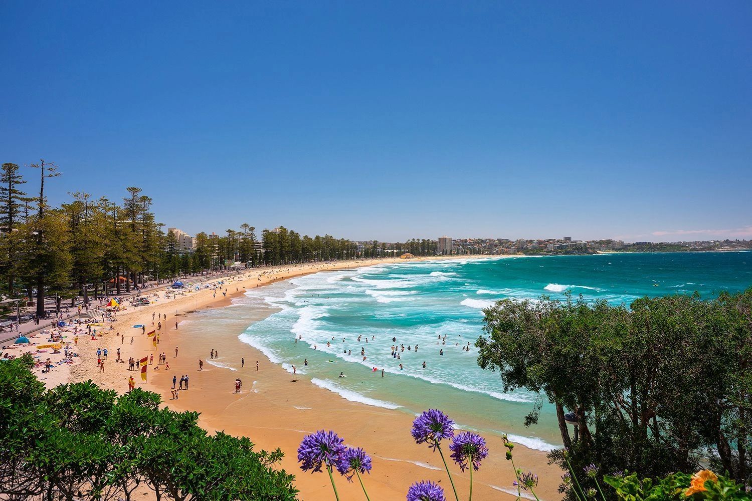 Sunny beach with turquoise waves and people enjoying the water and sand.