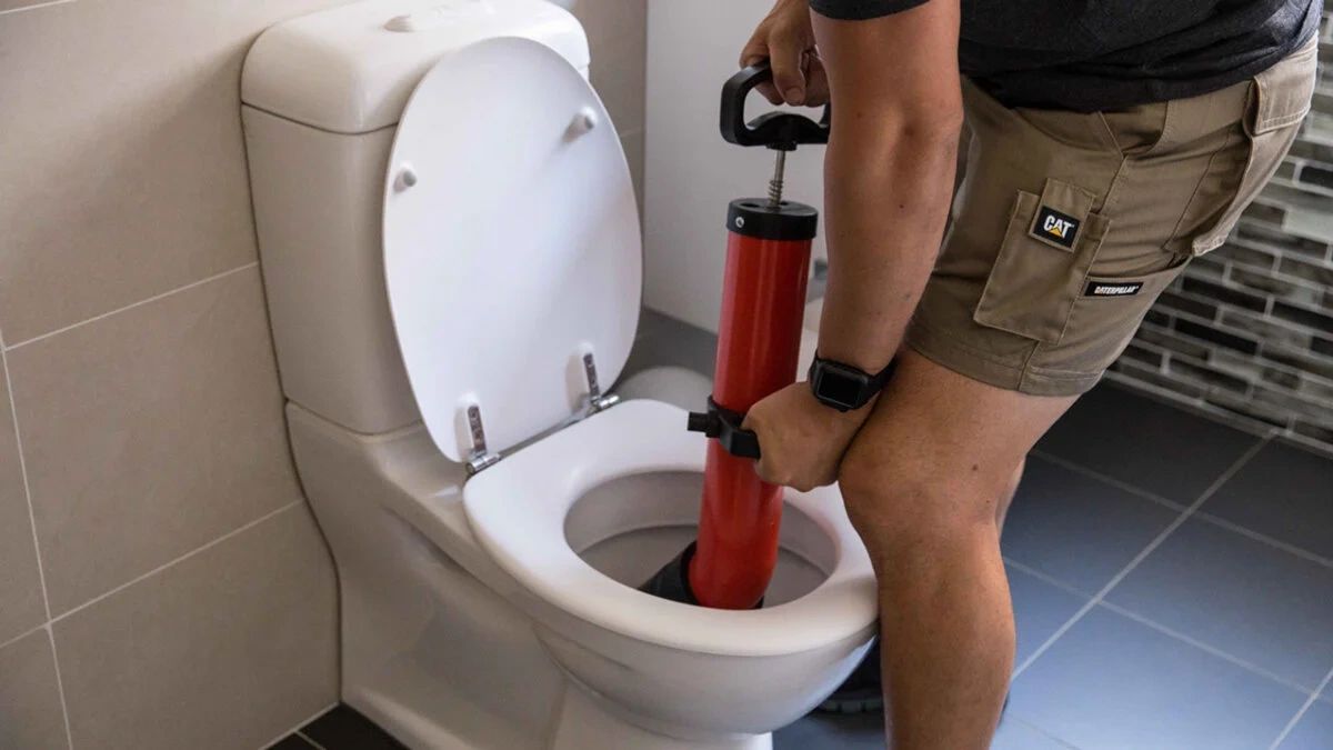 Person using a plunger to unclog a toilet.