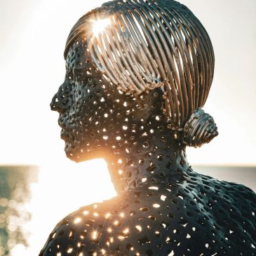 Metal sculpture of a woman's profile with sunlight shining through.