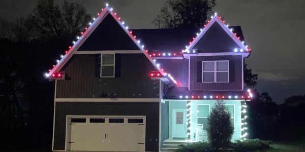 House decorated with red and white Christmas lights at night.