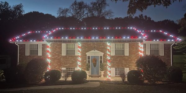 House decorated with red, white, and green Christmas lights at night.