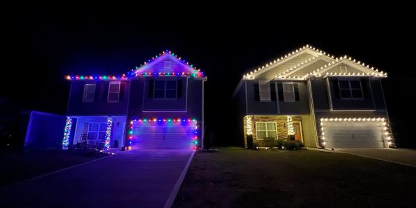 Two houses decorated with colorful Christmas lights at night.