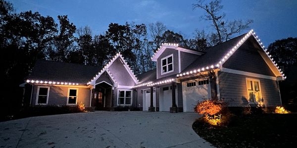 Suburban house decorated with white string lights at dusk.
