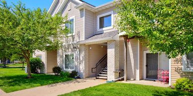 Sunlit townhouse entrance with greenery and outdoor seating.