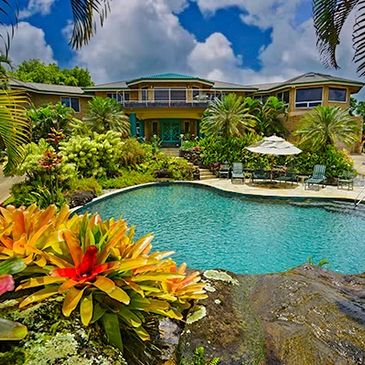 Luxurious tropical house with a vibrant garden and a clear swimming pool.