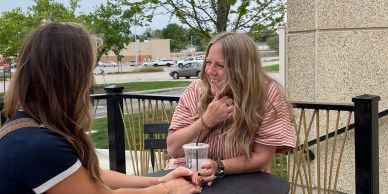 Two women chatting and laughing at an outdoor table.
