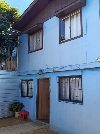 Two-story blue house with wooden door and barred windows.