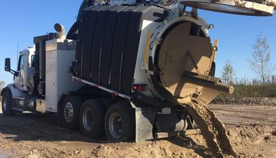 Truck pouring mud on a dirt road.