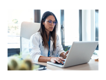 Doctor using laptop at desk.