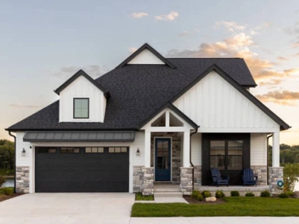 Modern farmhouse with white siding and black roof under a sunset sky.