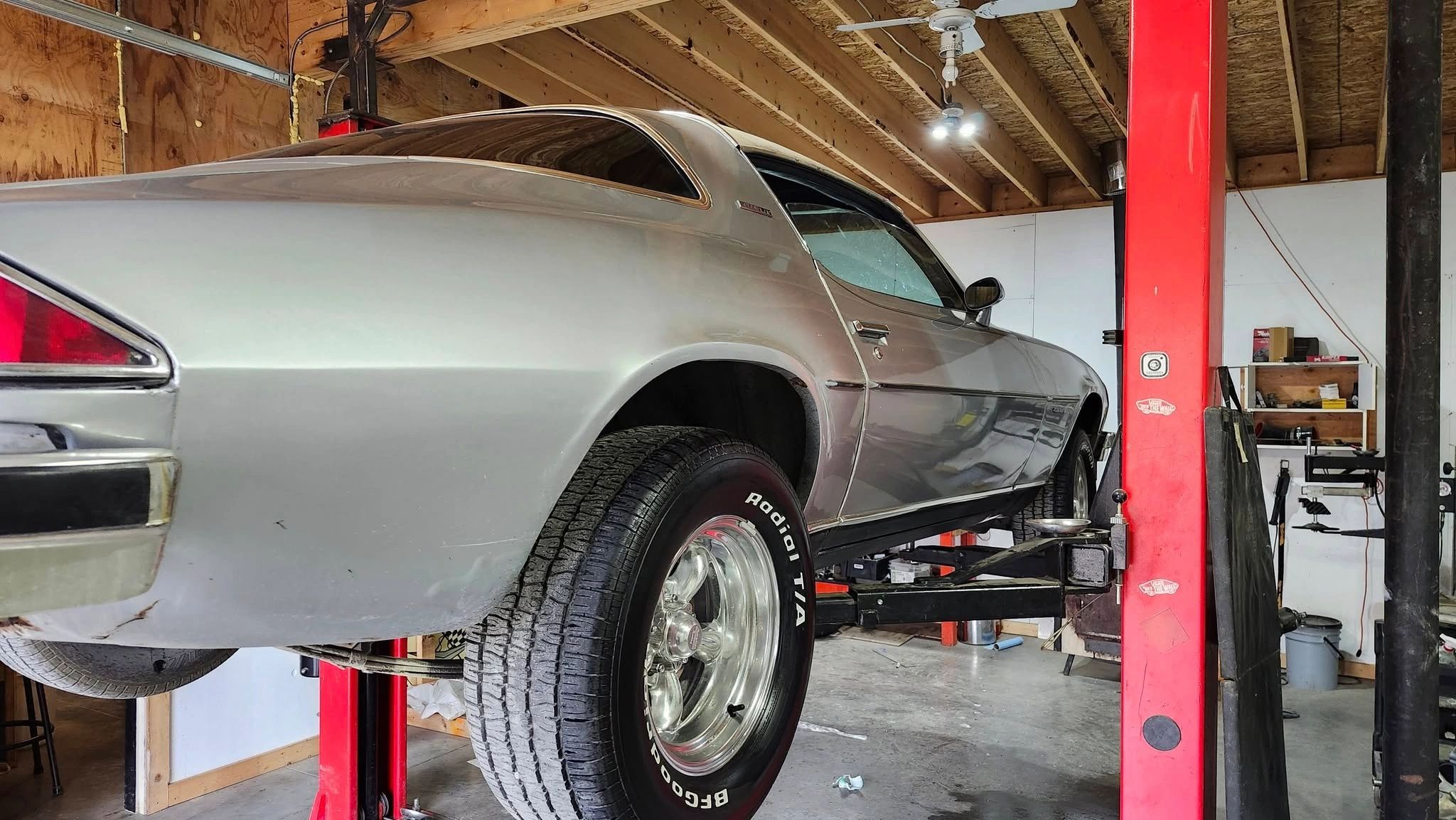 Classic silver car on a lift inside a garage.