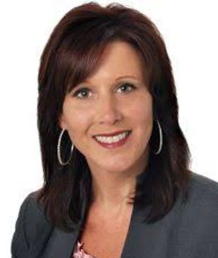 Professional woman with dark brown hair and hoop earrings smiling.