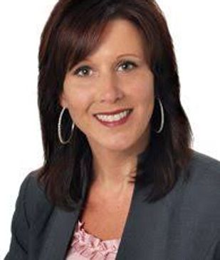 Professional woman with dark brown hair and hoop earrings smiling.