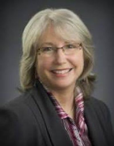 Professional woman with glasses smiling in a business portrait.
