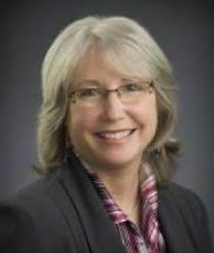Professional woman with glasses smiling in a business portrait.