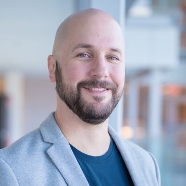 Smiling man in a suit and tie posing against a plain background.